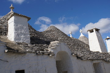 Fototapeta na wymiar Detail of white round house with specific architecture and stone roof from unesco world heritage Trulli of Alberobello in Italy