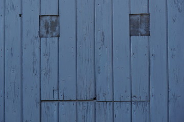A blue wooden board door that looks like a human face with eyes and mouth in southern Italy