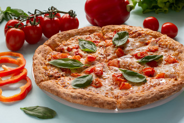 Pizza Margarita on a blue background with tomatoes and mozzarella. Still-life.