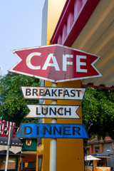 A set of street signs with coffee, breakfast, lunch, and dinner signs