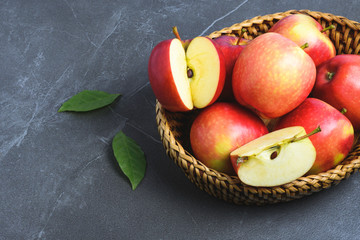 Group of apples and sliced in basket put on table and with leaves beside.