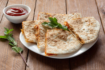 Mexican quesadilla with chicken, cheese, tomatoes and pepper on the table.