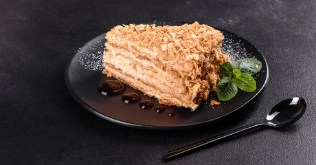 Fresh delicious cake napoleon with cream on a dark background