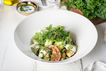 Eggplant salad with fresh herbs, served in a white plate