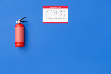 Fire extinguisher and evacuation plan on color background