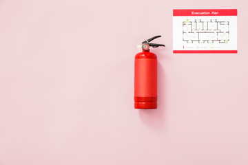 Fire extinguisher and evacuation plan on color background
