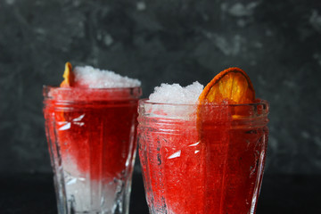 Bright, summer refreshing drink in a tall glass with crushed ice on a dark background. Top view with copy space.