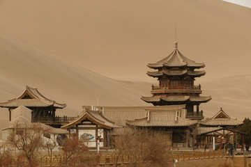 temple in china in the middle of desert with dunes in background , temple made with wood and very old style 