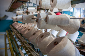A row of bobbins on a cotton spinning machine