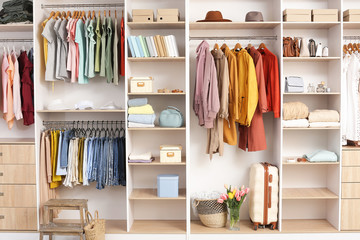 Big wardrobe with different clothes and accessories in dressing room