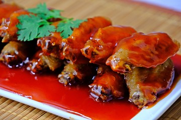 Close up stir fried chicken wings in red sauce.