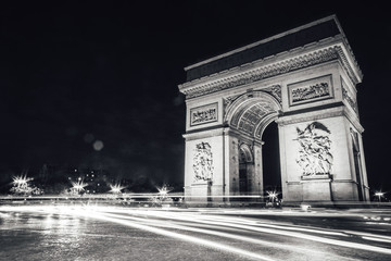 Arc de Triomphe at night with light trails from cars, in black and white.  Noir. No people - obrazy, fototapety, plakaty