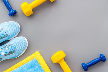 Athletics accessories. Dumbbells, towel, sneakers on grey background top-down copy space