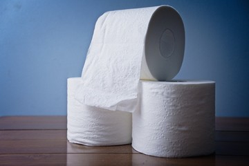 Three Rolls of Toilet Paper Stocked Up on Wooden Bathroom counter. Essential toiletries and basic necessity. Washroom products stock piled for pandemic. Coronavirus Covid 19 shopping rush. Soft TP 