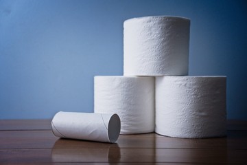 Empty toilet paper roll next to three full rolls on Wooden Bathroom counter. Essential toiletries and basic hygiene necessity. Washroom products stockpiled for sickness Soft TP 