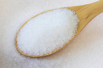 Fototapeta na wymiar Spoon wooden with white sand sugar on sugar background.