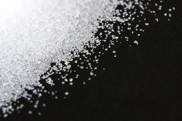 White sand sugar on black background with copy space.