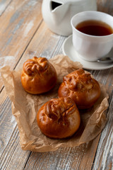 Traditional russian stuffed patties with golden crust, served on wooden table with a cup of tea