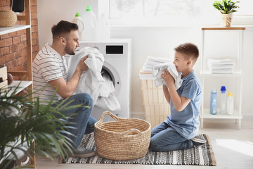 Man and his little son doing laundry at home - obrazy, fototapety, plakaty