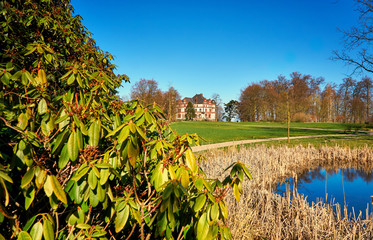 Obraz premium Rhododendron at the castle pond with Wiligrad Castle in the background. Germany