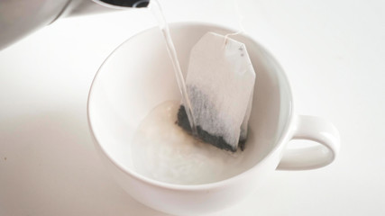 Shot tea bag is brewed in a white mug. Close up.