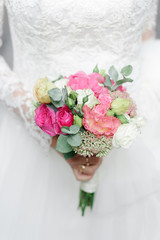 Portrait of a young beautiful bride in the old city. In the hands of a girl holding a wedding bouquet.