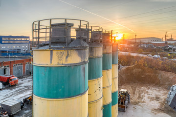 Obraz premium Silos for storage of cement aerial view. Evening shooting, the setting sun.