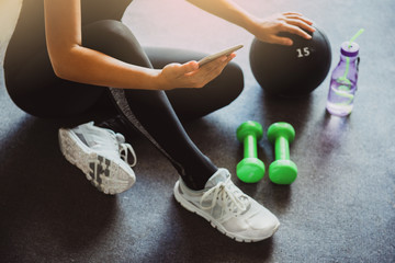 Woman using smartphone during workout at home in the living room. Online personal trainer or on mobile phone.Sport and recreation concept.advice to stop coronavirus COVID-19 spreading.