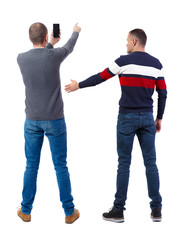 Obraz premium Back view of two man in sweater with mobile phone.