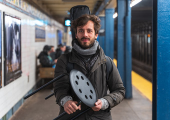 portrait of a man  Guitarist busker inside the new york city subway metro holding a stool with a...