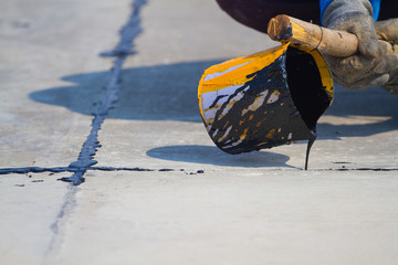 Worker sealing asphaltic joint for construction joint on concrete pavement, filling expansion joint concrete pavement.