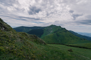 Fototapeta premium View of vast mountain range covered with green grass under a cloudy sky