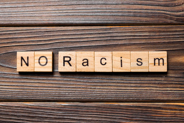 No racism word written on wood block. No racism text on table, concept