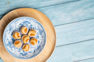 Fototapeta na wymiar Thai Traditional Cookie on Blue Dish and Wooden Round Board with Blue Rustic Old Wooden Table