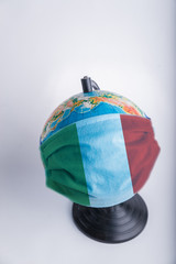 Globe in a medical mask with the flag of Italy. World pandemic concept