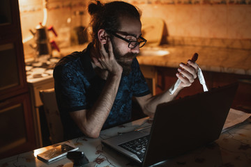 Stressed young hipster long hair bearded man is checking invoice in the kitchen.