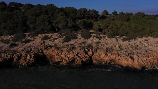 Aerial photography of rocks near the sea. People sitting on a rock near the sea. Sea waves on the beautiful coast of Spain.