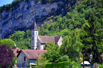Fototapeta premium Chanaz, France - August 10th 2016 : Focus on the church of the village, very close to a big rocky mountain.