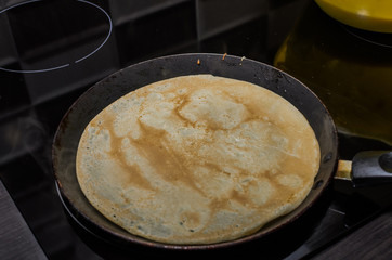 Pancakes are fried in a pan on an induction stove