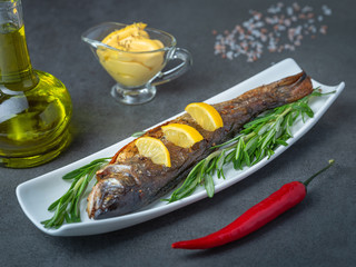 grilled trout with bottle of olive oil and herbs with cheese sauce