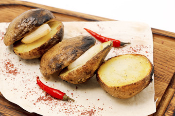 Sliced and fried potaes lined on a wooden board with lard inside. Potatoes decorated of red pepper.
