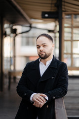 Portrait of fashionable well dressed man with beard posing outdoors