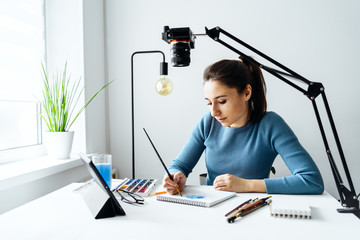 
Online content creator vlogger. A young women blogger with glasses removes the content for the blog, training courses. The concept of online learning to draw on walercolor