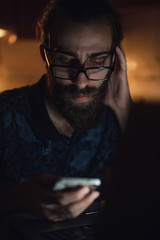Stressed young hipster long hair bearded man is checking invoice in the kitchen.