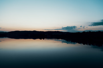 Sunset over the Danube with the mountains as a silhouette in the background, swan swims in the water