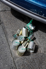 barattoli legati ad un auto sull'asfalto simbolo di buon augurio per gli sposi © alex.pin