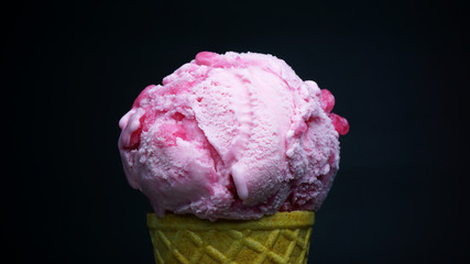 Strawberry ice cream scoop in waffle cone on black background, Front view Food concept.