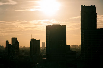 beautiful warm toned color of sky  and the sun on a top of silhouette buildings  in  a city .photo with some noise and gain