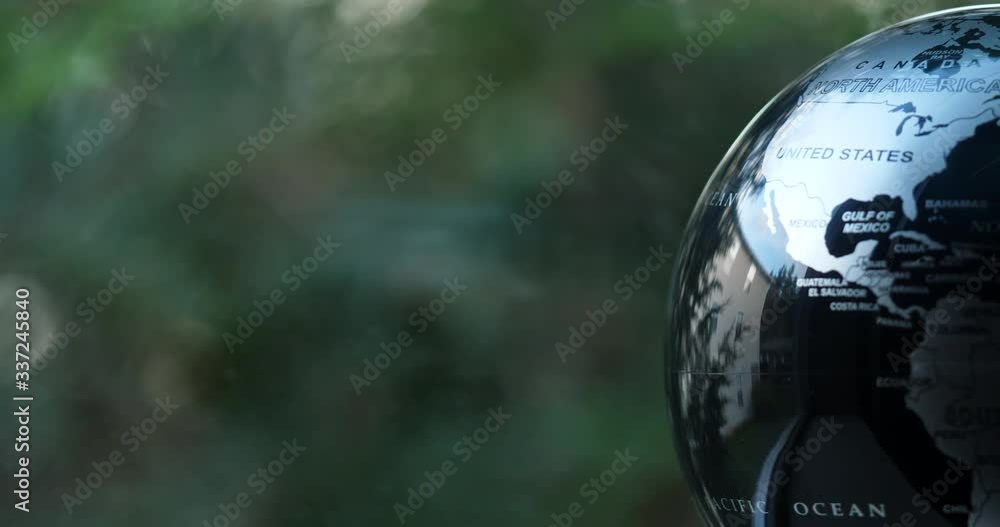 Wall mural earth globe spinning slowly next to a window with trees moving genitally in the wind
