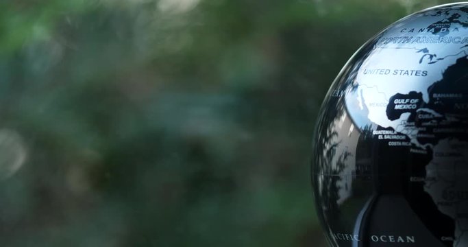 Earth globe spinning slowly next to a window with trees moving genitally in the wind